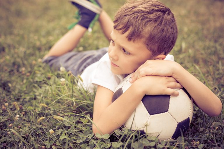 サッカーボールと寝そべる少年